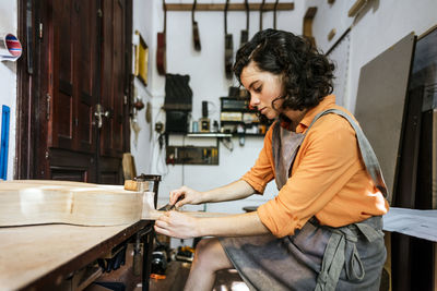 Woman luthier making guitars in her musical instrument workshop