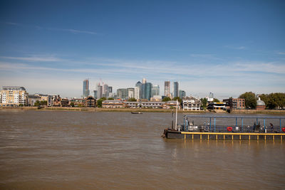 Scenic view of river by buildings against sky