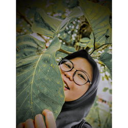 Close-up portrait of young woman with leaves