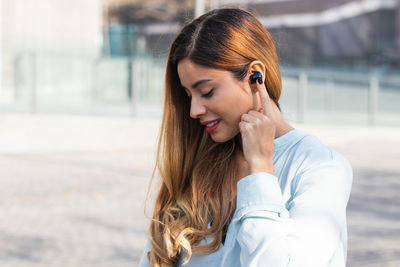 Portrait of young brunette business woman outdoors using earphones while working. business concept