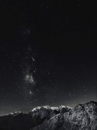 Scenic view of snowcapped mountains against star field at night