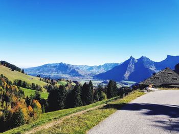 Road by mountains against clear blue sky