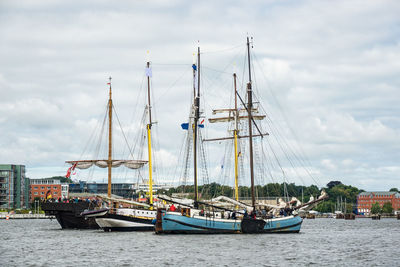 Sailboats moored on harbor against sky