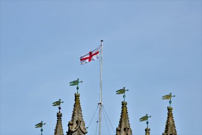 Low angle view of flags against clear blue sky