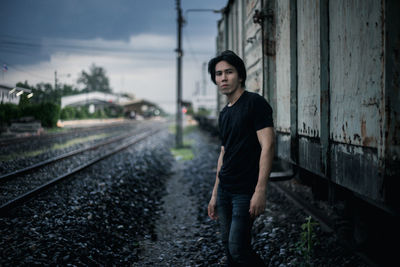 Portrait of young man standing on railroad track