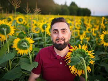 Portrait of young man picking yellow flowers