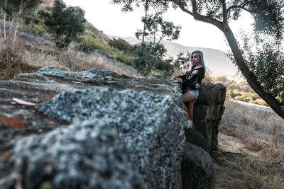 Full length of young woman sitting on rock