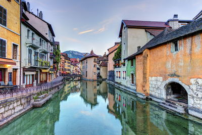 Canal amidst buildings in city against sky