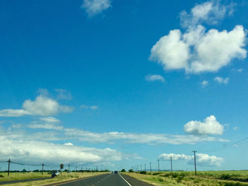 Road amidst field against sky