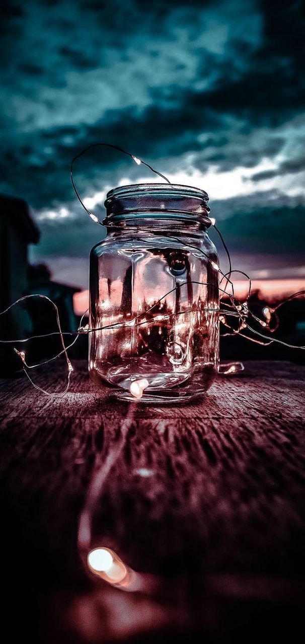 glass - material, no people, table, selective focus, close-up, transparent, still life, illuminated, lighting equipment, nature, food and drink, indoors, cloud - sky, technology, wood - material, candle, container, food, light, glass, personal accessory