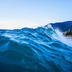 Scenic view of waves against sky during sunset