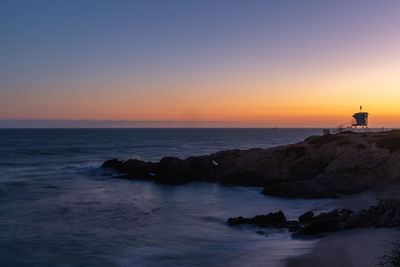 Malibu sunset behind a lifeguard tower on a rocky coastline