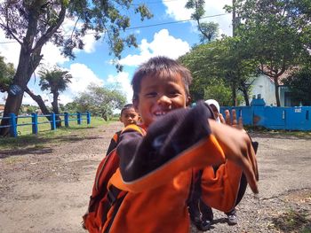 Portrait of smiling boy standing against trees