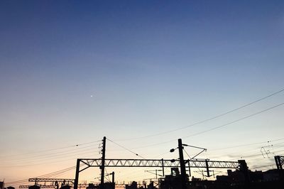 Silhouette of electricity pylons against clear sky