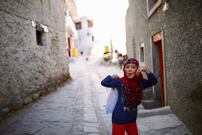 Portrait of smiling young woman standing against building