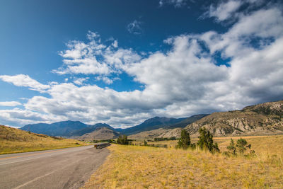 Road leading towards mountains against sky