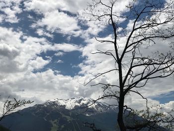 Low angle view of bare tree against cloudy sky