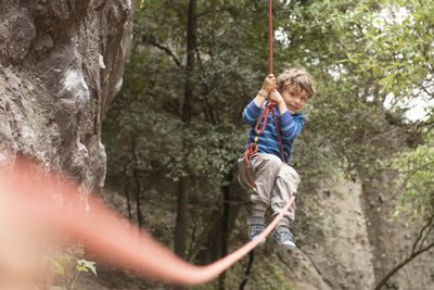 Four year old toddler swings hanging from a climbing rope