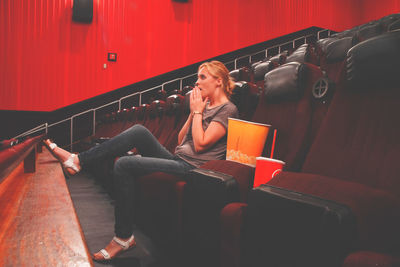 Full length of young woman sitting at theatre