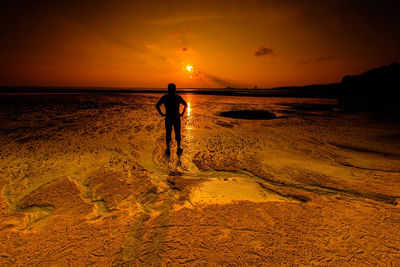 Silhouette man standing on beach against sky during sunset