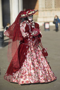 Woman wearing costume and standing on street during festival