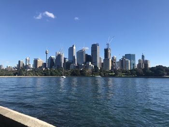 Sea by modern buildings in city against sky