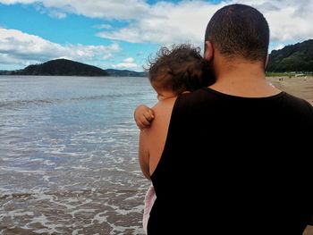 Two men at beach against sky