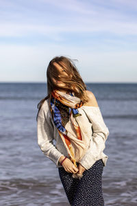 Midsection of woman standing in sea against sky