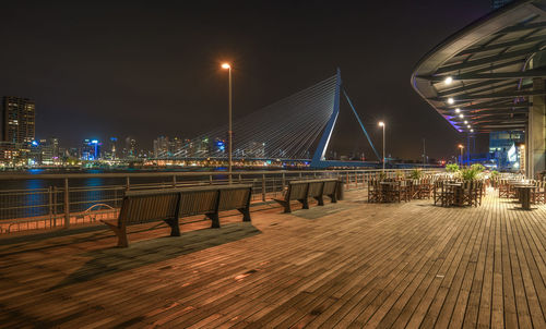 Benches at promenade by erasmusbrug against sky at night