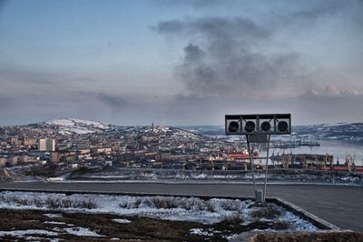 Scenic view of frozen river in city against sky during winter