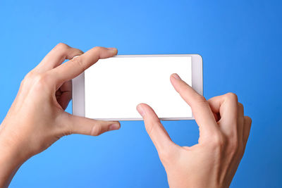 Midsection of man using mobile phone against blue sky