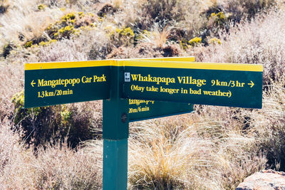Close-up of information sign on grass against sky