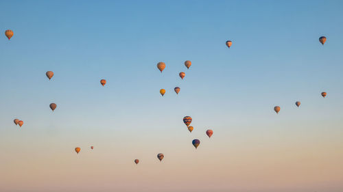 Low angle view of balloons flying against sky during sunset