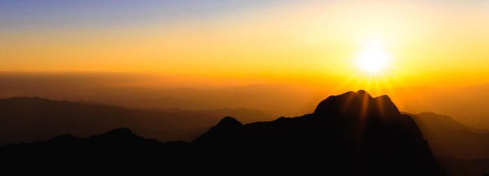 A stunning sunset or sunrise scene of silhouette mountain peaks and ridge background