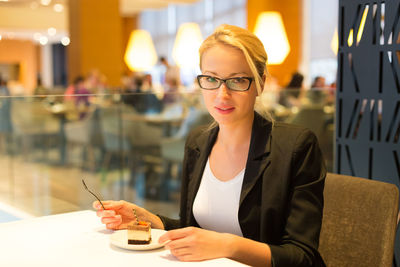 Portrait of smiling woman eating while sitting at restaurant