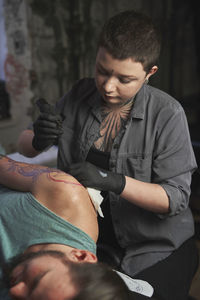 Female tattoo artist making tattoo
