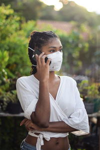 Young black woman in face mask speaking on the phone