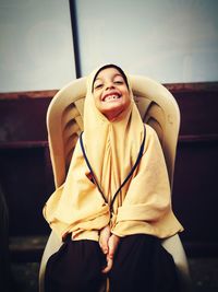 Portrait of smiling girl standing against wall