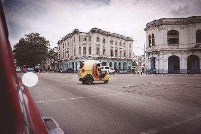 Cars on city street against sky