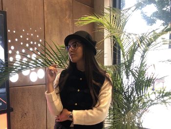 Young woman looking away while standing against illuminated tree