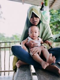 Father and baby sitting on a man looking at camera