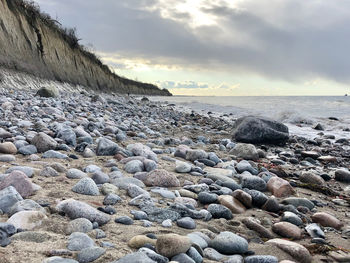 Rocks on beach against sky during sunset