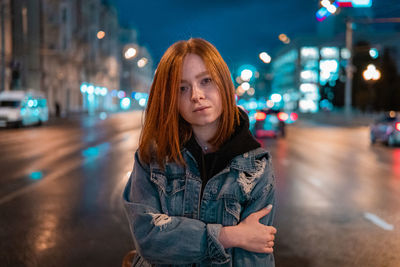 Portrait of woman standing against illuminated light at night