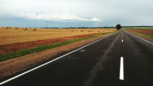 Road amidst field against sky