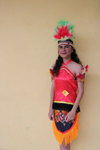 Portrait of young woman standing against wall