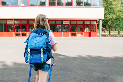 Back view of a schoolgirl with a school backpack on her back going to school.