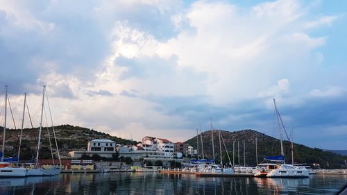 Sailboats moored at harbor against sky