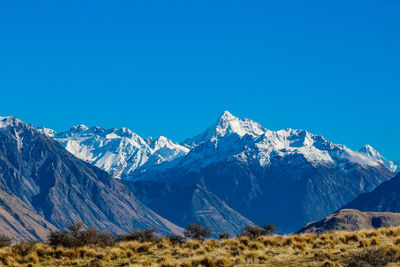 Scenic view of snowcapped mountains against clear blue sky