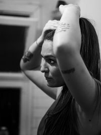 Close-up of young woman looking away while holding her hair at home