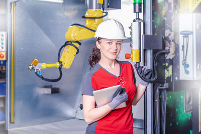 Portrait of smiling technician standing by machinery in factory